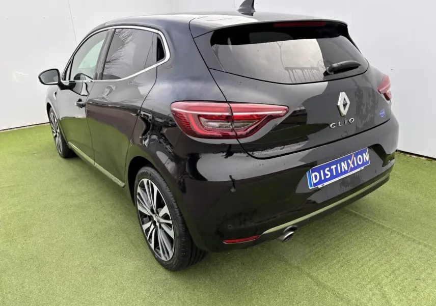 Vue 3/4 arrière gauche d'une Renault Clio noire étoile avec jantes alliage et échappement chromé sur sol vert.