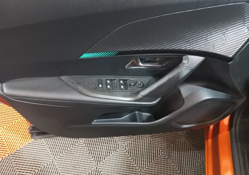 Gros plan sur la porte côté conducteur noire avec insert décoratif bleu d'une Peugeot 2008 orange 2021.