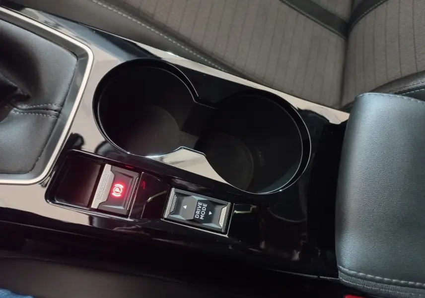 Gros plan sur la console centrale noire de la Peugeot 2008 avec frein à main électrique et bouton Drive Mode.