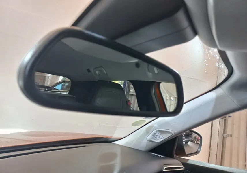 Vue intérieure du rétroviseur central d'un Peugeot 2008 orange 2021, avec siège arrière et partie du tableau de bord visibles.