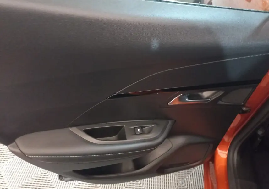 Intérieur de la porte côté gauche d'une Peugeot 2008 orange 2021, avec garniture noire et bouton de verrouillage.