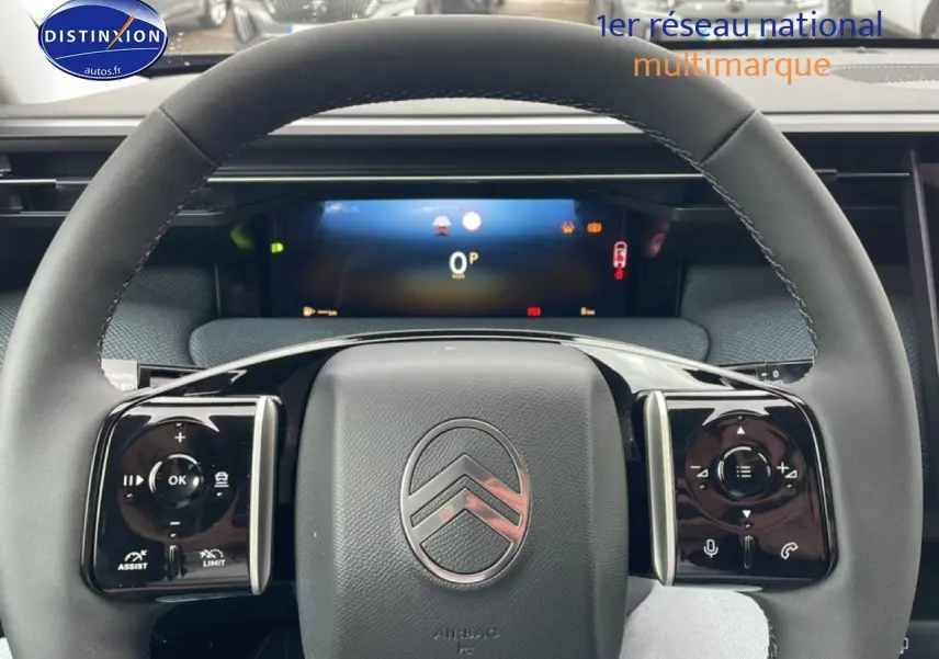 Vue rapprochée du volant multifonction noir du Citroën C5 Aircross 2026 avec tableau de bord numérique en arrière-plan.