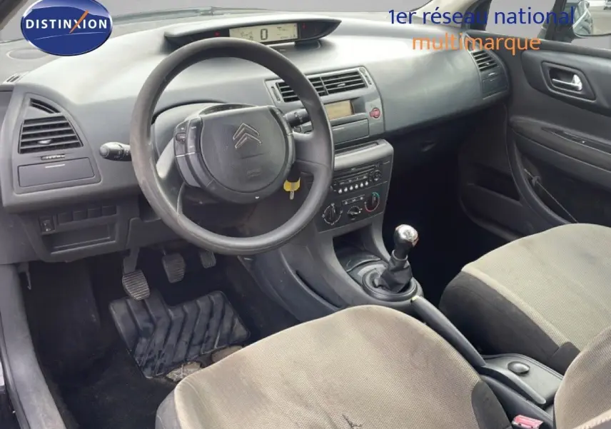Intérieur de Citroën C4 Coupé 2009 vu côté conducteur, volant, tableau de bord gris et sièges tissu gris clair.