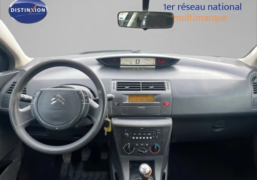 Vue intérieure avant centrée sur le tableau de bord gris et volant de la Citroën C4 Coupé noir métal de 2009 avec boîte manuelle.