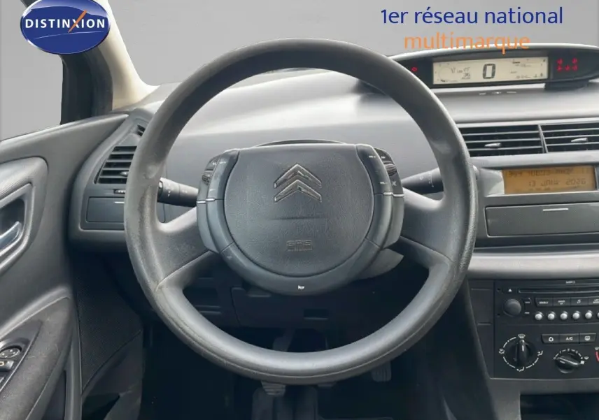 Vue intérieure centrée sur le volant et tableau de bord d'une Citroën C4 Coupé 2009, ambiance sobre et fonctionnelle.