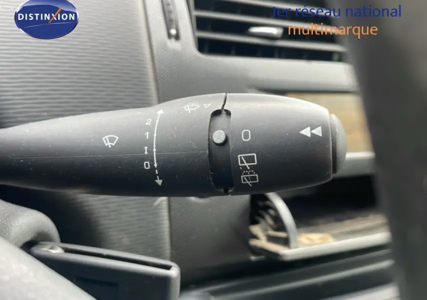 Gros plan sur la commande d’essuie-glace à gauche du volant dans l’habitacle d’une Citroën C4 noir métal de 2009.