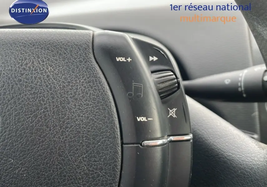 Gros plan sur les commandes audio au volant d'une Citroën C4 Coupé noire métal de 2009, intérieur en tissu gris.