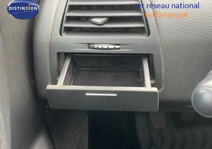 Gros plan sur la boîte à gants ouverte du tableau de bord d'une Citroën C4 noire métal de 2009.