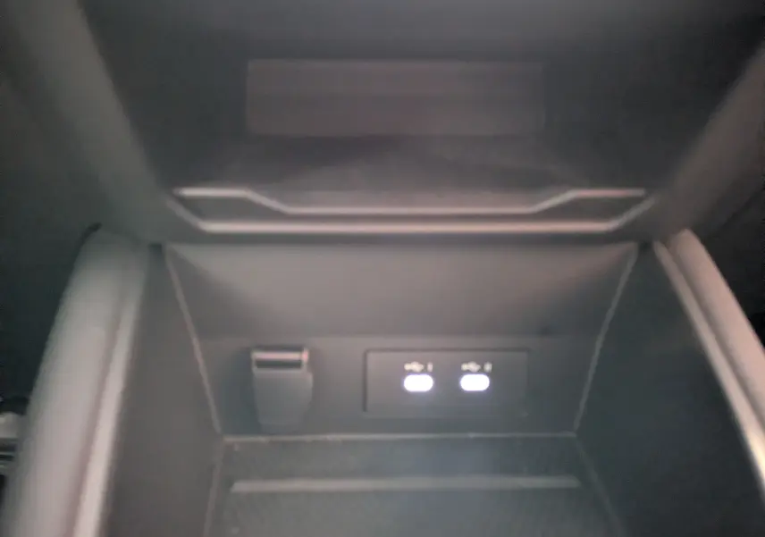 Gros plan sur la console centrale du Renault Symbioz 2025, montrant deux ports USB éclairés et une prise 12V, intérieur noir.