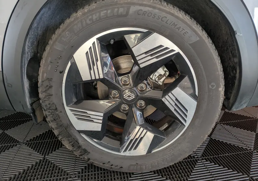 Gros plan sur la roue avant droite du Renault Symbioz gris Cassiopée, jante alliage bicolore au design géométrique.