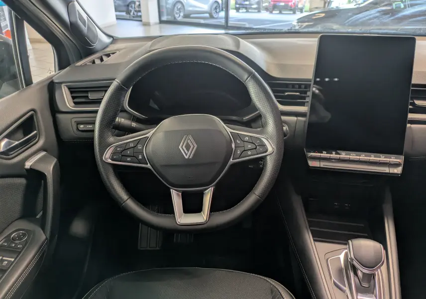 Vue intérieure centrée sur le volant noir du Renault Symbioz 2025 avec écran tactile vertical et levier de vitesse.