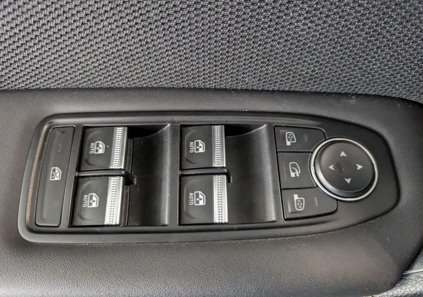 Gros plan sur les commandes de lève-vitres et réglage des rétroviseurs sur la portière intérieure noire du Renault Symbioz gris cassiopée.