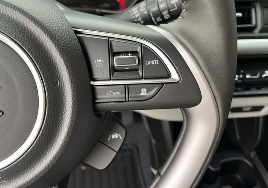 Gros plan sur le volant cuir multifonctions gris et ses commandes d’aide à la conduite de la Suzuki Swift 2026.