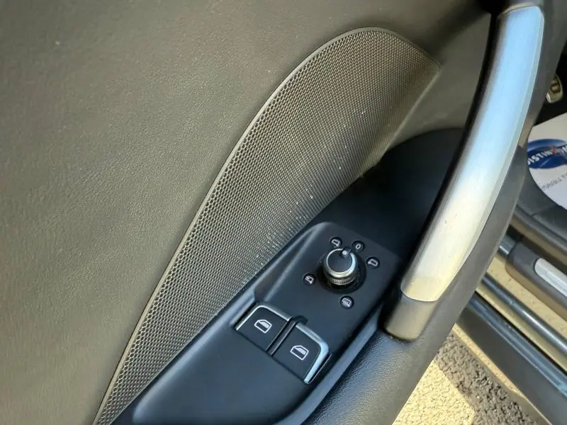 Détail de la porte avant gauche noire de l'Audi TT Coupé 2016 avec commandes des vitres et rétroviseurs.