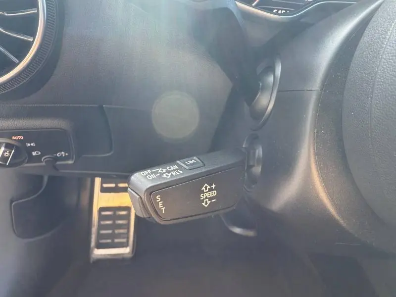 Gros plan sur la commande de régulateur de vitesse à gauche du volant dans l'habitacle noir de l'Audi TT Coupé 2016.