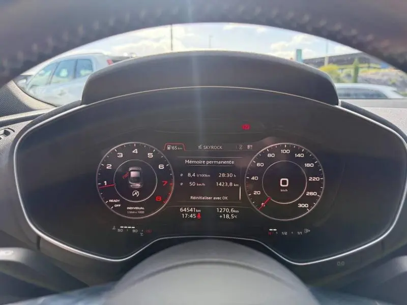 Vue rapprochée du tableau de bord numérique d'un Audi TT Coupé 1.8 TFSI 2016, affichage des compteurs et informations de conduite.