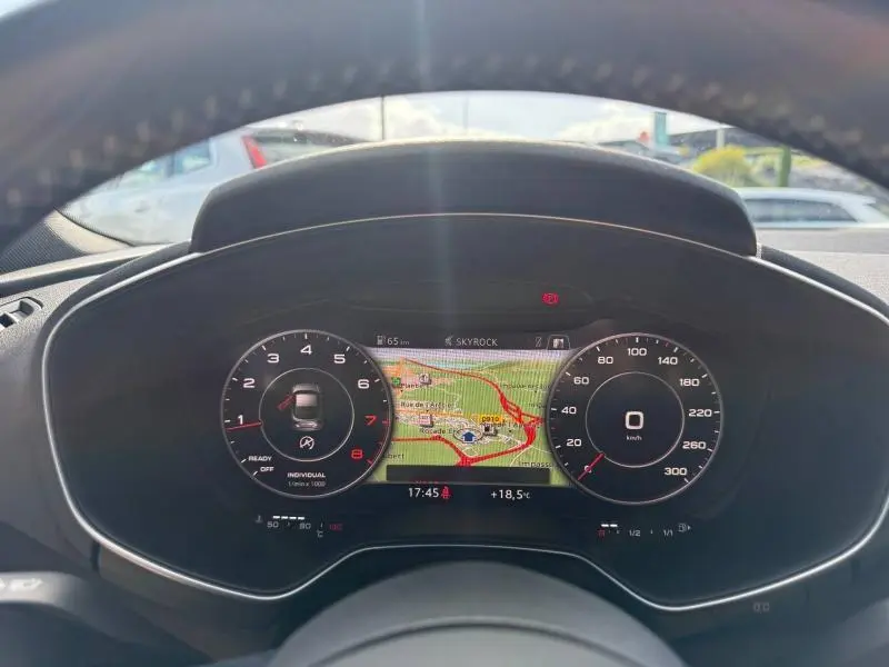 Vue rapprochée du tableau de bord numérique de l'Audi TT Coupé 2016, affichant un GPS coloré et compte-tours à gauche.