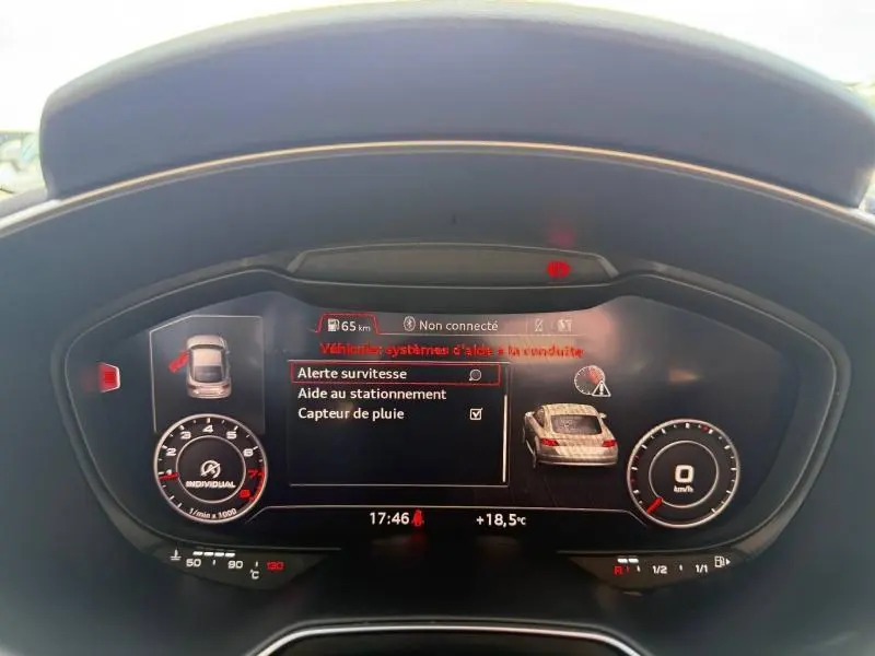 Vue rapprochée du tableau de bord numérique d'une Audi TT Coupé 2016, affichant les alertes et la température extérieure.