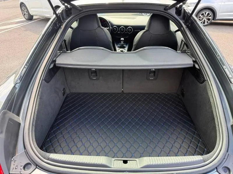 Coffre ouvert vu de l'arrière d'une Audi TT Coupé gris foncé, montrant l'intérieur et la console centrale.