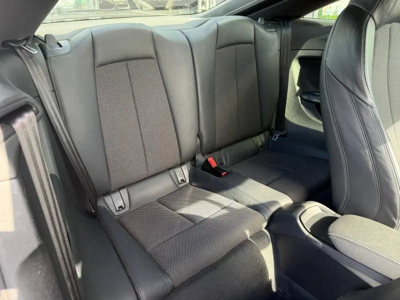Vue intérieure arrière de l'Audi TT Coupé 2016, sièges sport noirs en cuir et tissu avec ceintures de sécurité visibles.