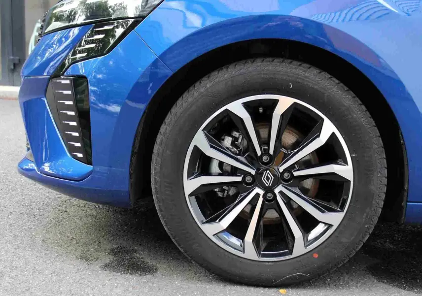 Gros plan sur la roue avant droite d'une Renault Clio bleu iron metal avec jante alliage bicolore moderne.