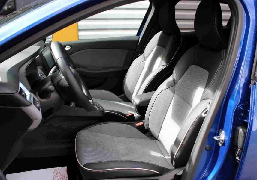 Vue intérieure côté conducteur de la Renault Clio 2025 bleu Iron Metal, sièges tissu gris noir avec surpiqûres contrastées.