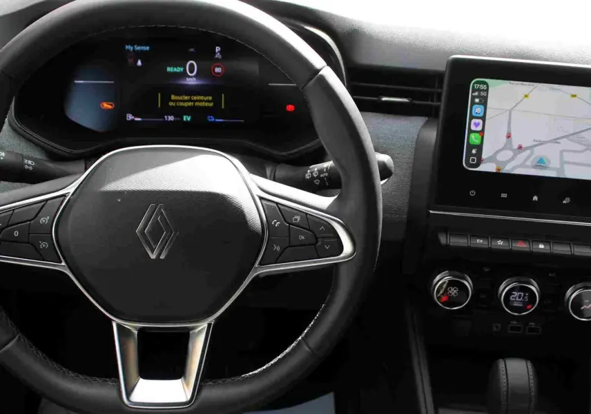 Vue rapprochée du volant et du tableau de bord numérique de la Renault Clio hybride, avec écran tactile et commandes intégrées.