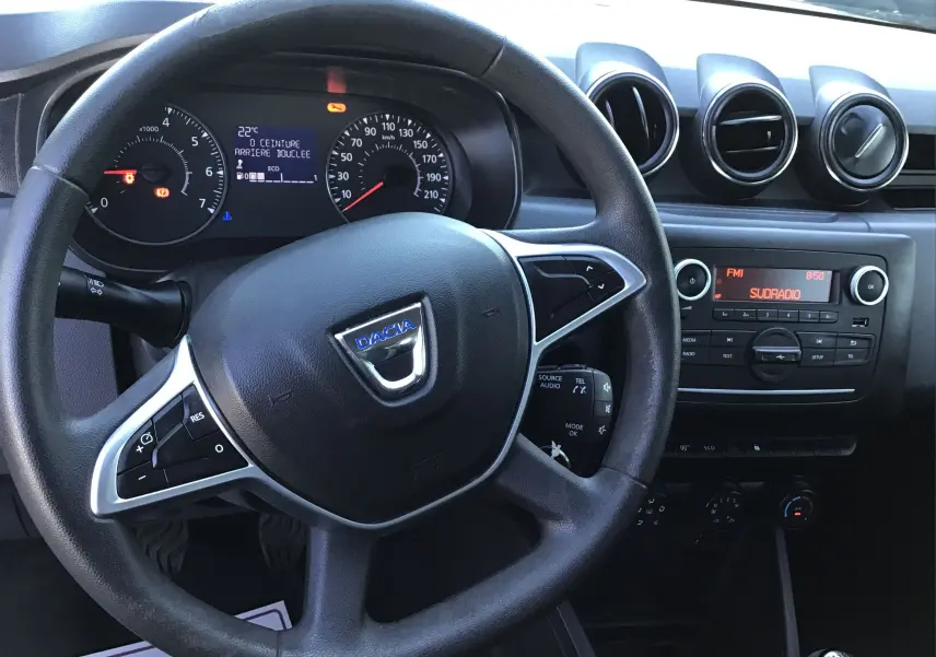 Vue intérieure centrée sur le volant noir du Dacia Duster 2021 avec tableau de bord et console radio visibles.