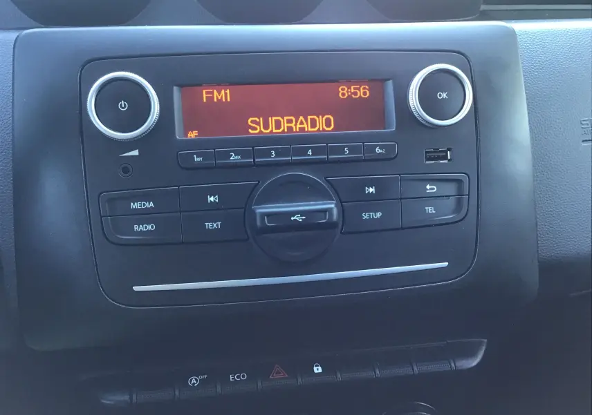 Vue rapprochée de la console centrale noire du Dacia Duster 2021, affichant la radio Sudradio sur écran orange.
