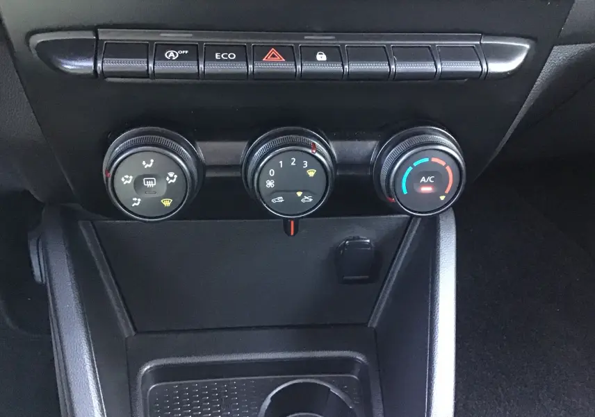 Vue rapprochée des commandes de climatisation et boutons fonctionnels du tableau de bord du Dacia Duster 2021.