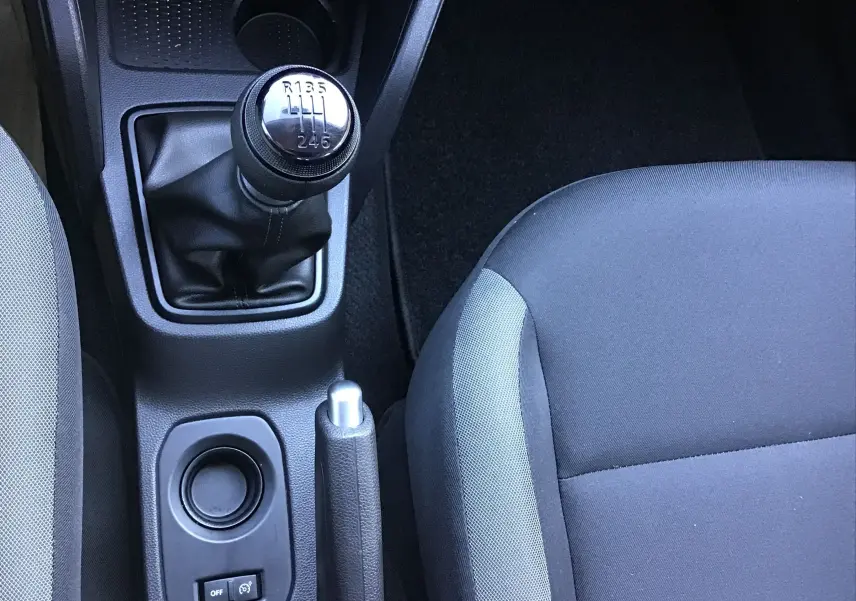 Vue intérieure centrée sur le levier de vitesses manuel et le frein à main du Dacia Duster blanc 2021, version Eco-G.