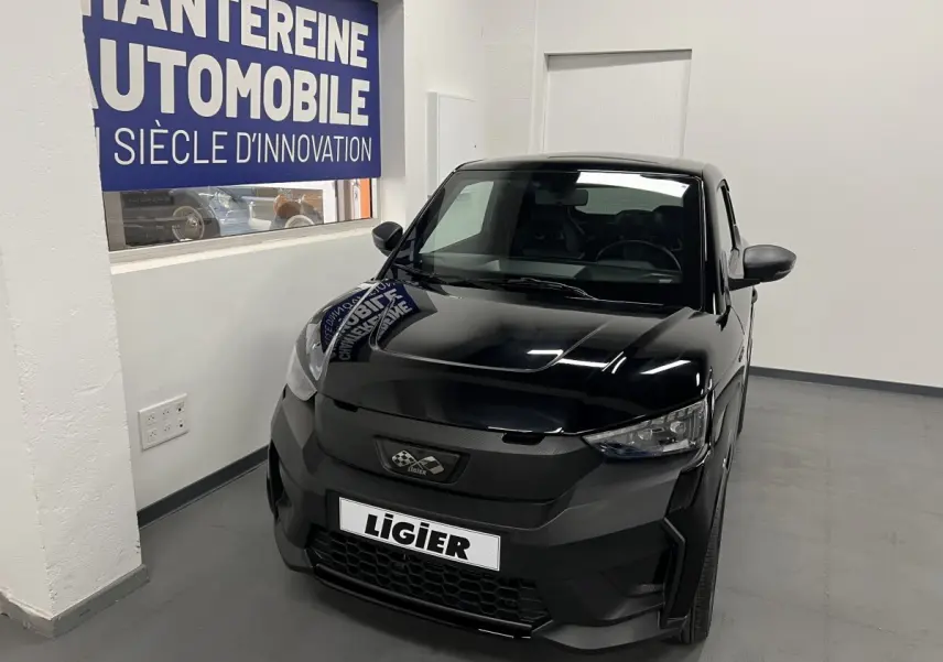 Vue 3/4 avant d'une Ligier JS50 noire 2026 avec calandre noire mate et phares LED dans un showroom.