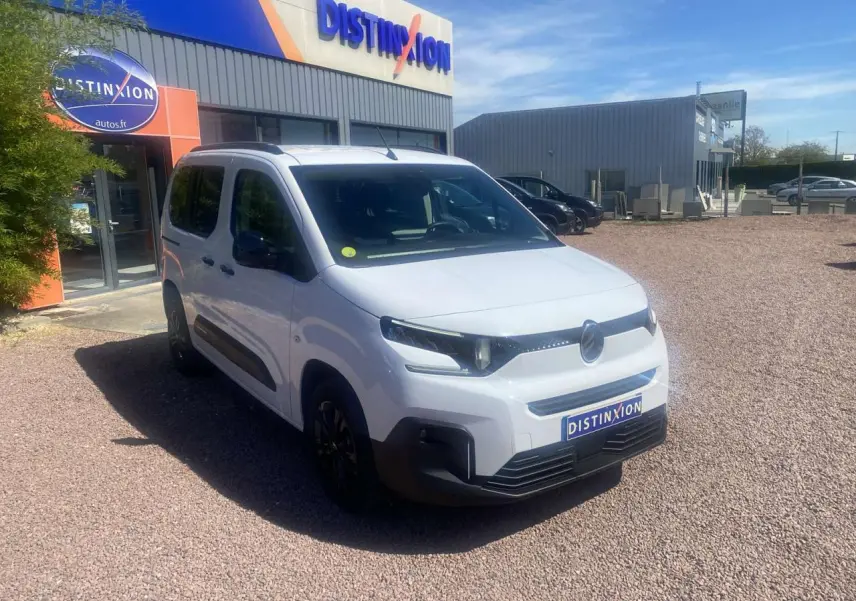 Vue 3/4 avant d'un Citroën Berlingo blanc 2025 avec portes coulissantes, stationné devant un bâtiment Distinxion.