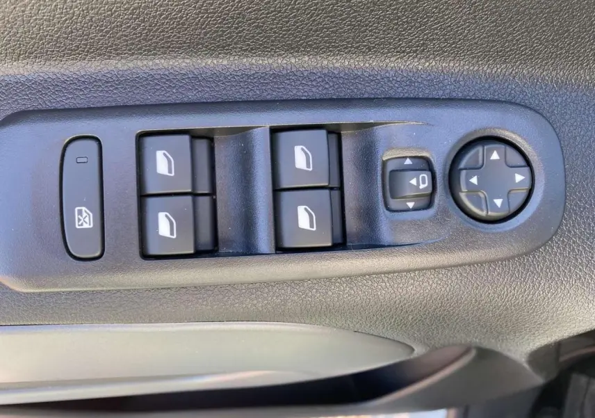 Gros plan sur les commandes des vitres électriques et réglages des rétroviseurs côté conducteur du Citroën Berlingo blanc 2025.