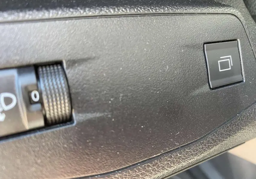 Gros plan sur le bouton de réglage des phares et la commande de l'écran tactile dans l'habitacle du Citroën Berlingo blanc 2025.