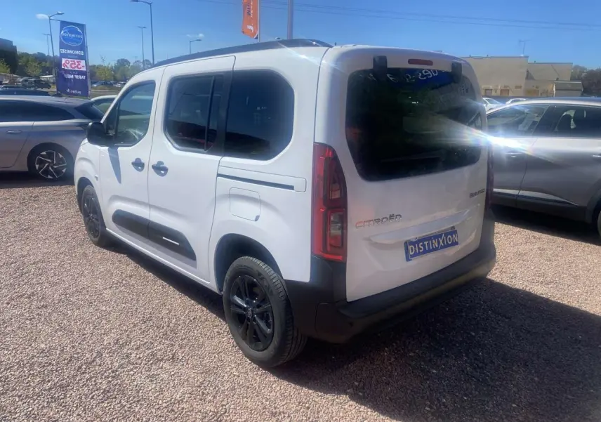 Vue 3/4 arrière droite du Citroën Berlingo blanc 2025 avec portes coulissantes et jantes noires sur parking.