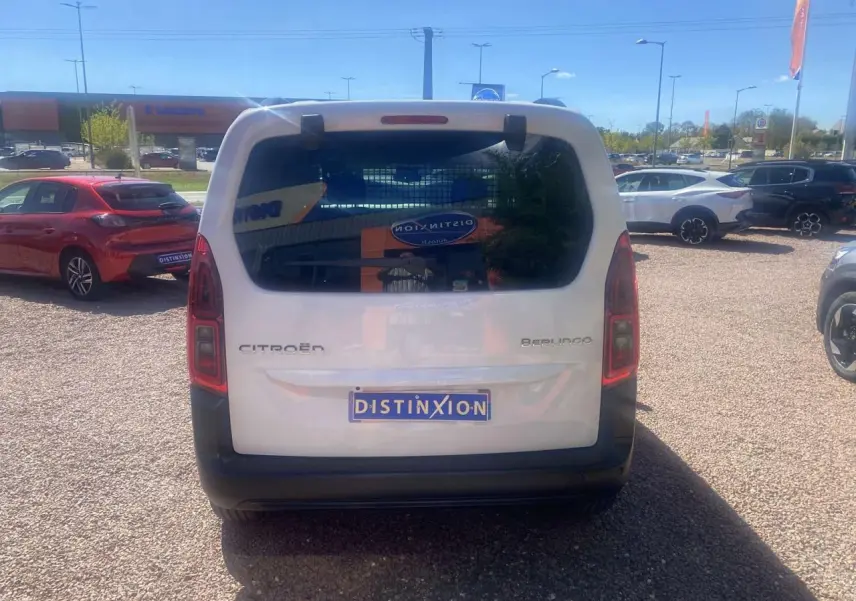 Vue arrière d'un Citroën Berlingo blanc 2025 avec hayon vitré et plaque Distinxion sur un parking extérieur.