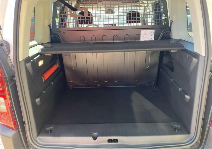 Vue arrière du coffre spacieux du Citroën Berlingo blanc 2025 avec séparation métallique et tablette amovible.
