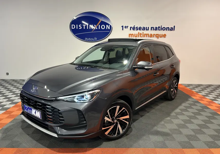 Vue 3/4 avant droite du MG ZS Hybrid+ 197 Luxury gris Candem avec toit panoramique ouvrant en showroom.
