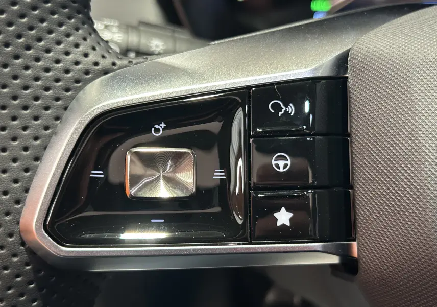 Gros plan sur les commandes noires et argentées au volant perforé du MG MOTOR ZS Hybrid+ 197 Luxury Candem Grey.