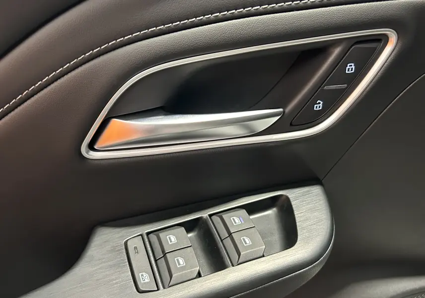 Gros plan sur la poignée intérieure et les commandes de fenêtre côté conducteur du MG Motor ZS Hybrid+ 2026 en cuir noir.