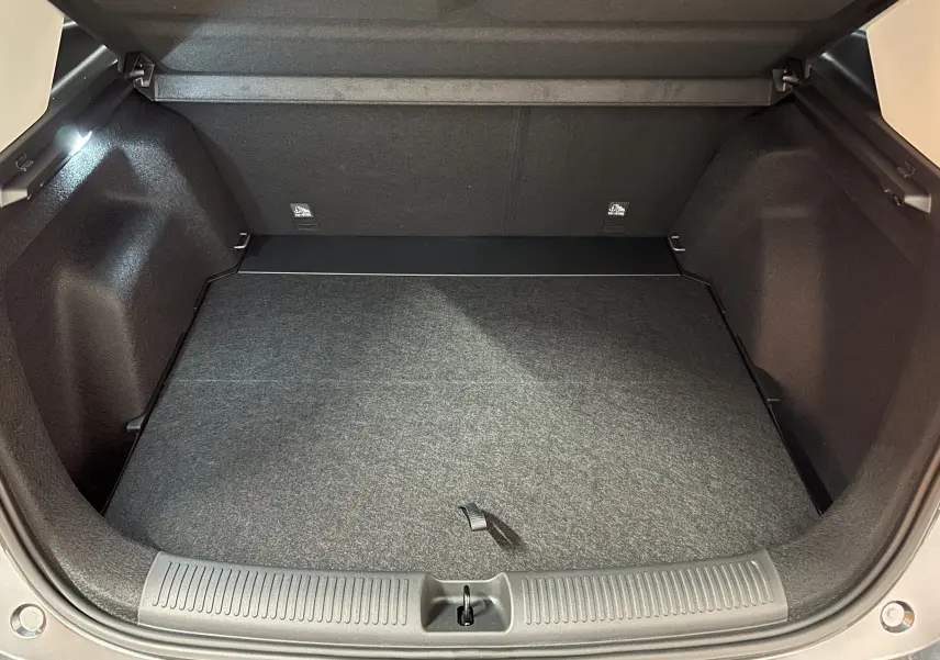 Coffre ouvert vu de l'arrière d'un MG MOTOR ZS Hybrid+ 197 Luxury gris Candem, espace de chargement vide et propre.