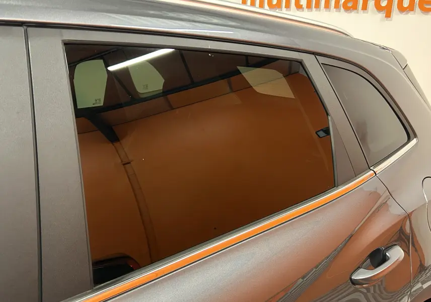 Vue rapprochée du côté gauche arrière d’un MG ZS Hybrid+ 197 Luxury gris Candem avec vitres teintées et poignée de porte visible.