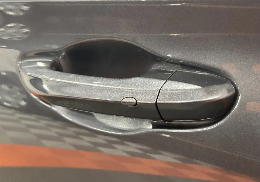 Poignée de porte côté gauche du MG Motor ZS Hybrid+ 197 Luxury en couleur Candem Grey avec finition lisse et bouton intégré.