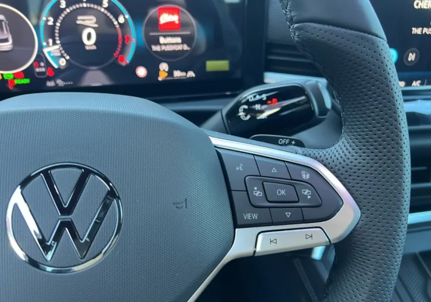 Gros plan sur le volant cuir perforé noir du Volkswagen T-Roc 2026 avec commandes multifonctions et tableau de bord digital.
