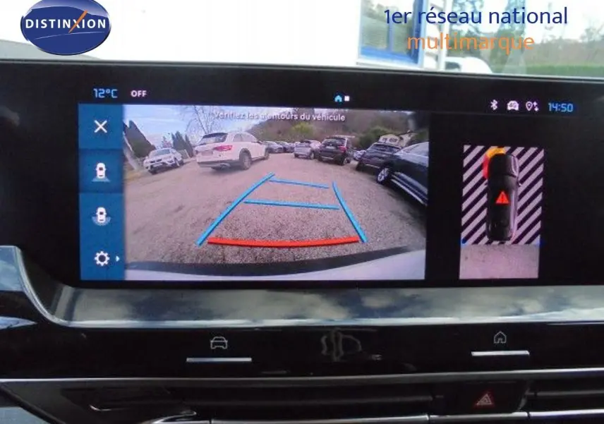 Vue de la caméra de recul du Citroën C5 X blanc métal, affichant les lignes de guidage sur un parking extérieur.