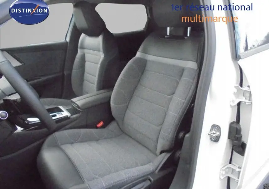 Vue intérieure côté conducteur d'une Citroën C5 X blanche métal, sièges tissu gris et cuir noir, console centrale visible.