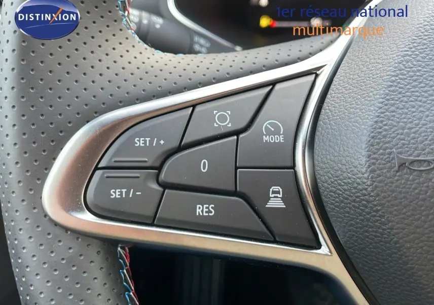 Gros plan sur les commandes au volant du Renault Captur E-Tech hybride 2025, cuir noir perforé avec surpiqûres tricolores.