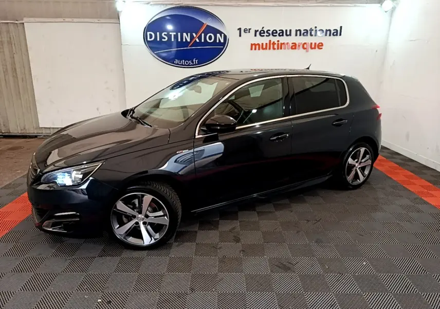 Peugeot 308 GT Line gris foncé vue de profil côté gauche dans un showroom avec éclairage intérieur.
