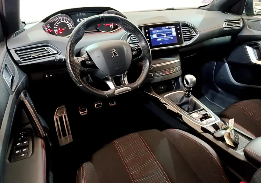Intérieur noir de la Peugeot 308 GT Line 2016, vue côté conducteur, volant cuir et écran tactile central visible.